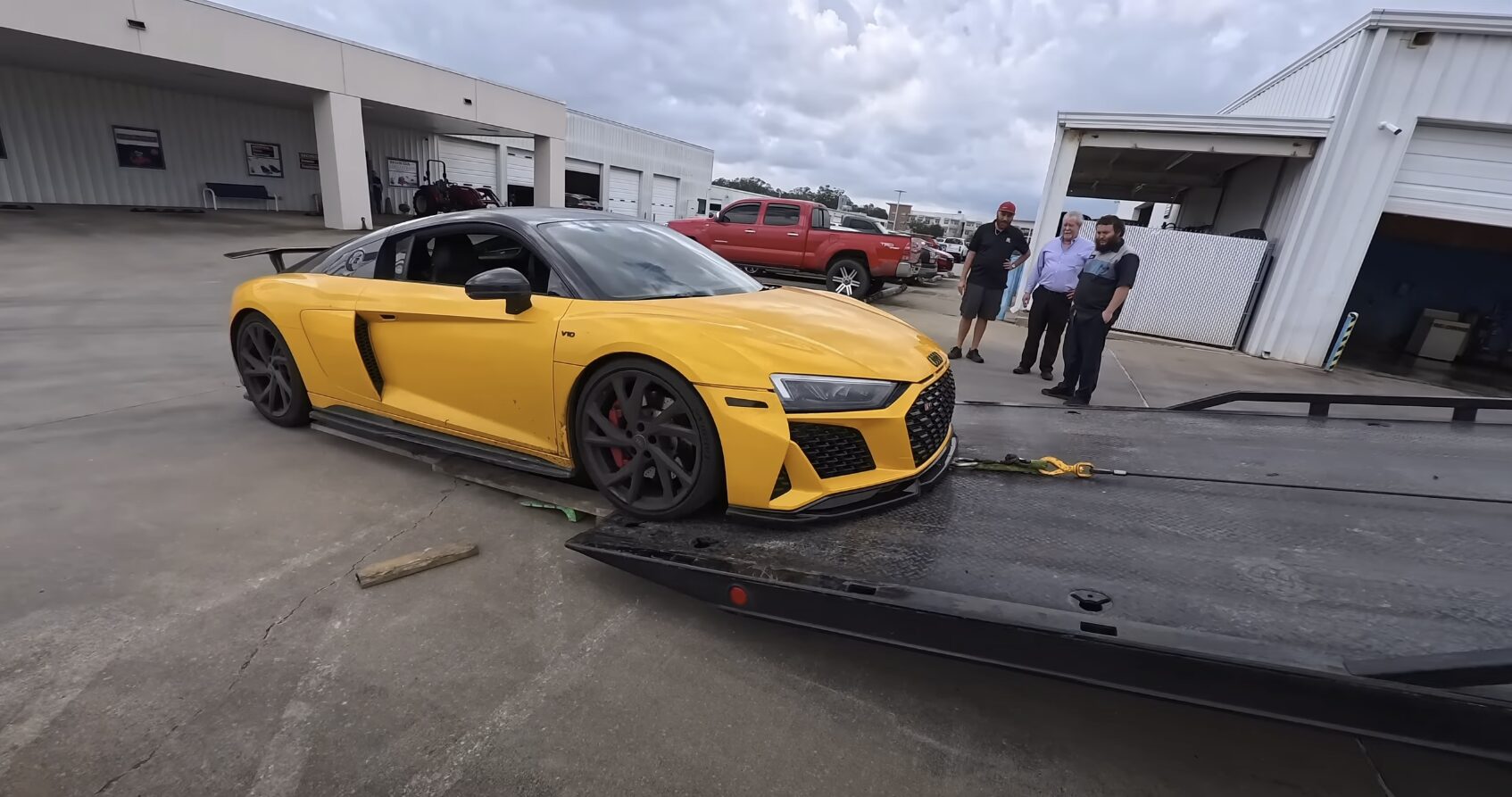 Yellow luxury sports car being loaded onto professional flatbed trailer for long-distance transport