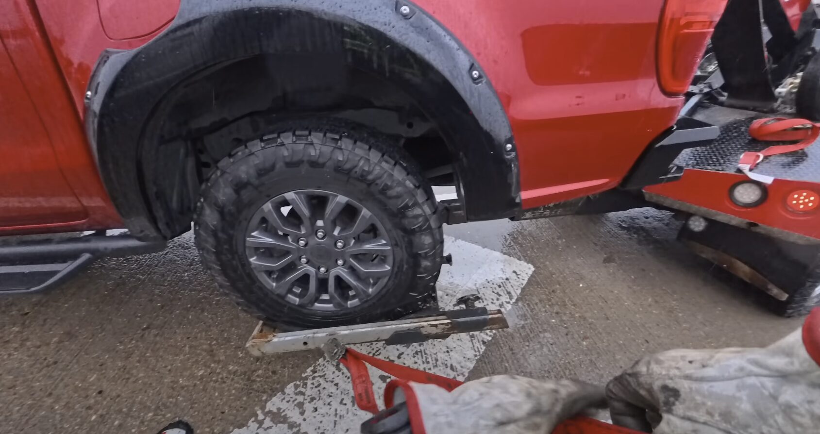 Damaged red pickup truck being prepared for junk car removal and recycling