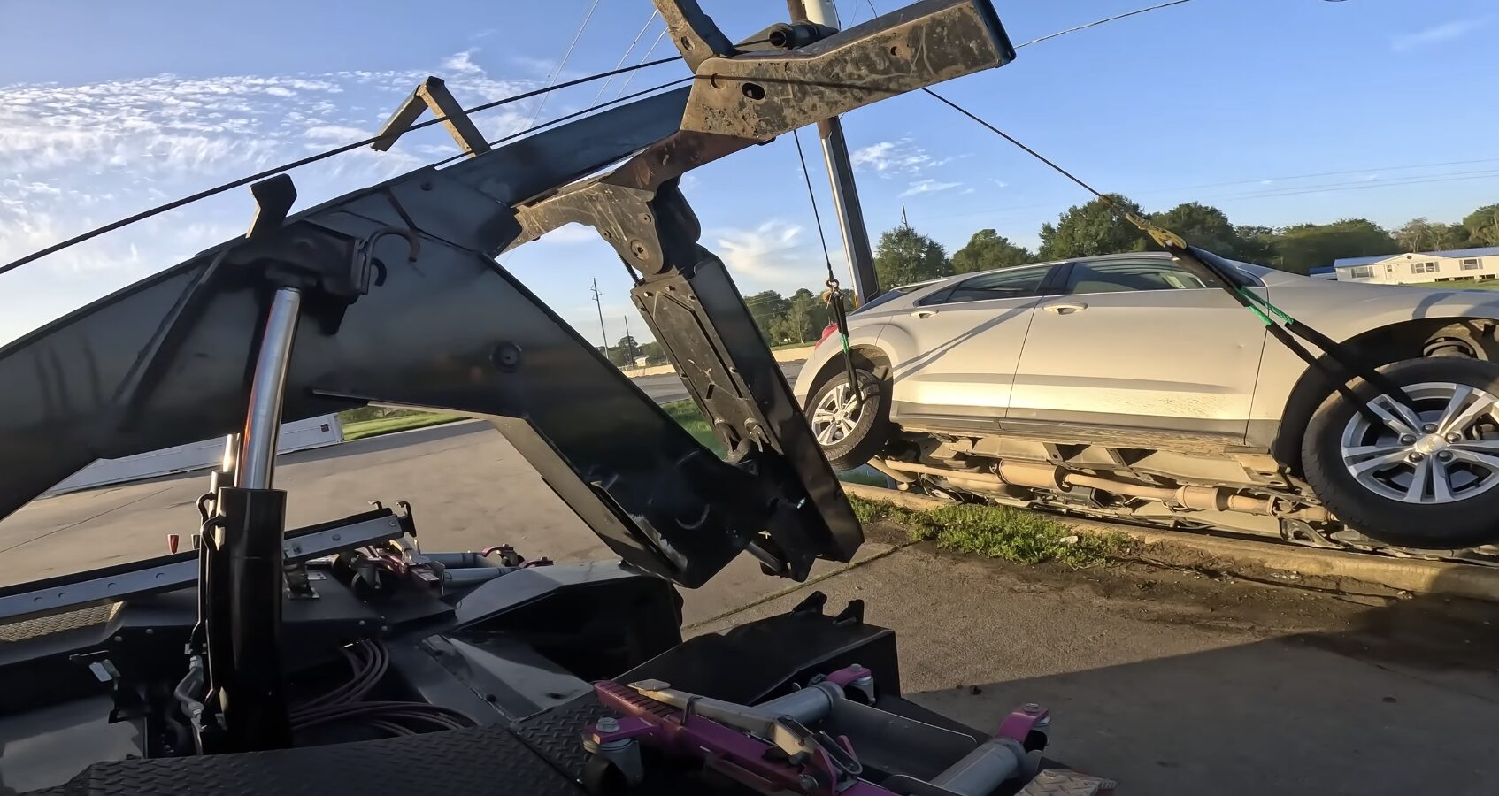 Car being secured on flatbed tow truck showing professional towing equipment and safety measures