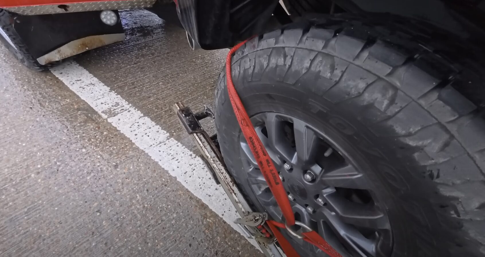 Professional Vehicle Towing with Proper Safety Equipment Professional tow truck with red towing straps securing a vehicle wheel